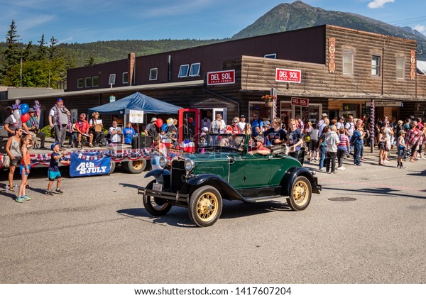 Skagway, Alaska / United States - July 4 2018:\
families watch Fourth of July Parade with antique green car passing\
the reviewing stand