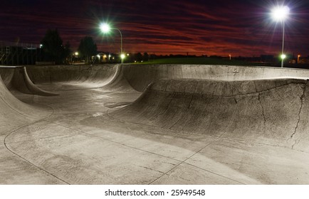 A Skate Park At Night With Lights On And Sunset Sky.