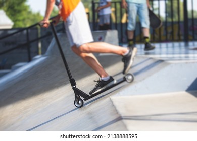 Skate Park View With Kids On A Kick Scooter Doing Tricks And Stunts, Boys In A Skate Park Riding Bmx Bike And Skate, Playing And Enjoying Summer On New Ramp, Teenagers Skateboarders And Bmx Riders 