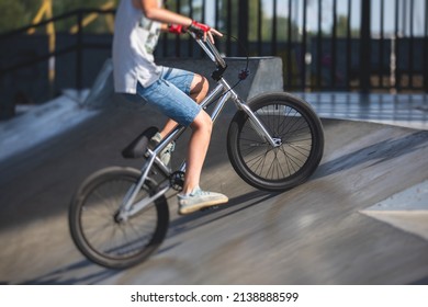 Skate Park View With Kids On A Kick Scooter Doing Tricks And Stunts, Boys In A Skate Park Riding Bmx Bike And Skate, Playing And Enjoying Summer On New Ramp, Teenagers Skateboarders And Bmx Riders 