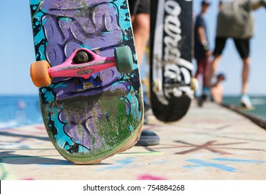 Skateboard With Graffiti Drawing. Old Used Skate Board For Extreme Skating. Group Of Young Skaters Standing On Ramp Top Ready To Ride. Skater With Deck In Skatepark. UKRAINE-1 AUGUST,2017: