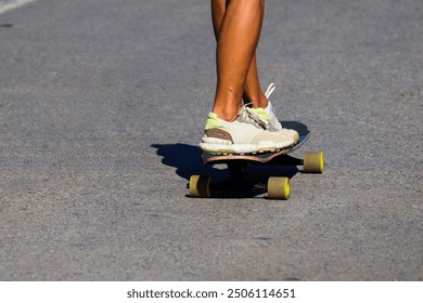 Skateboard. Woman riding a skateboard. Women's athletic legs on a skateboard. Bright sneakers and a colorful skateboard. Skateboarding. - Powered by Shutterstock