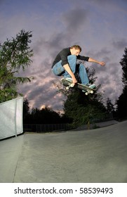 skateboarder jumping high at full speed at the skatepark after sunset(slightly motion blurred).