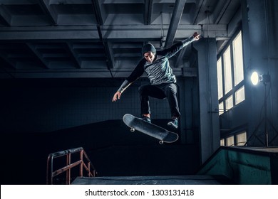 Skateboarder Jumping High On Mini Ramp At Skate Park Indoor.