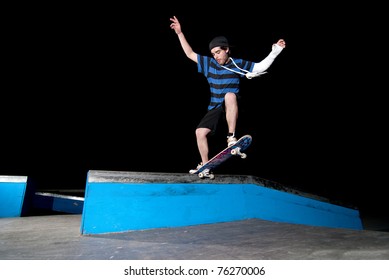 Skateboarder On A Slide At Night At The Local Skatepark.