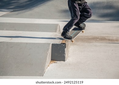 A skateboarder performs a grind trick at an urban skatepark, balancing on a concrete ledge. Captured mid-action, this dynamic shot showcases skateboarding skill and urban youth culture. - Powered by Shutterstock