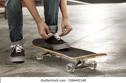 Skateboarder tying shoes at skate park - Powered by Shutterstock