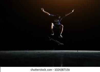 Skater Boy Jumping On Black Background With Skateboard Trick