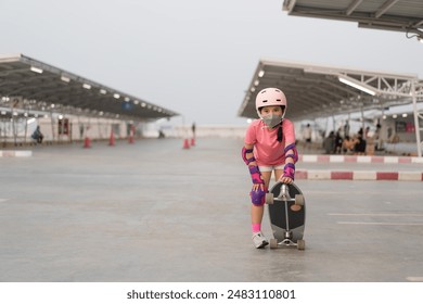 skater by asian child or kid girl playing surf skate or skateboard in skatepark or sport public park at parking to wearing face mask protect pm 2.5 dust with helmet elbow wrist knee guard body safety - Powered by Shutterstock