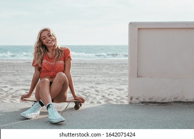 skater girl sitting on a skateboard at malibu beach
