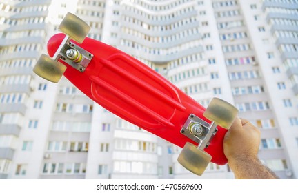 Skater Hand  Holding Red Skateboard Deck  On White House  Background