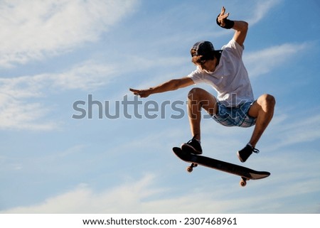 Skater jumps high in air on background blue sky