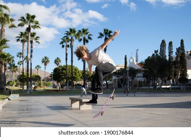Skater perform a kickflip while riding his skateboard at the skatepark
				