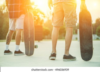 Skaters friends outdoor in urban city with skateboards in their hands - Young people training longboard extreme sport - Friendship concept - Focus on right man's hand holding board - Warm filter - Powered by Shutterstock