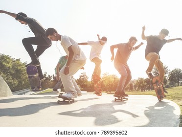 Skaters Jumping With Skateboard In City Suburb Park - Sporty Guys Performing Tricks And Skills At Sunset In Urban Contest - Extreme Sport And Youth Lifestyle Concept - Main Focus On Center People