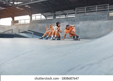 Skaters Resting After Skateboarding At Skatepark. Friends In Casual Outfit Sitting On Skateboards. Extreme Sport As Active Urban Lifestyle. - Powered by Shutterstock