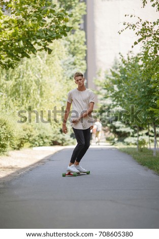 Similar – Young man riding on skate and holding surfboard