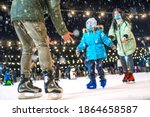 Skating rink. Family wearing the medical face masks on the ice rink. Prevention of coronavirus and other infectious diseases during the winter holidays concept. Mom and dad teach daughter to skate.