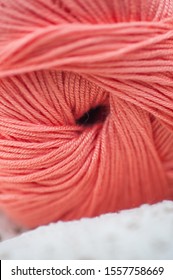 Skein of bamboo thread of living coral vertical. Shallow depth of field macro photograph, selective focus. Concept: Knitting hobby, trending colors, color impact