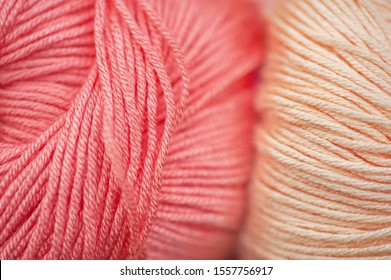 Skeins of bamboo thread of living coral and creamy beige macro background. Shallow depth of field macro photograph, selective focus. Concept: Knitting hobby, trending colors, color impact 