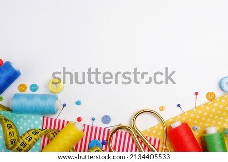 Skeins of sewing thread, multicolored buttons, scissors, needles, thimble, fabric, zipper on a white background.The concept of manual labor,clothing repair,sewing,embroidery,sale of sewing accessories