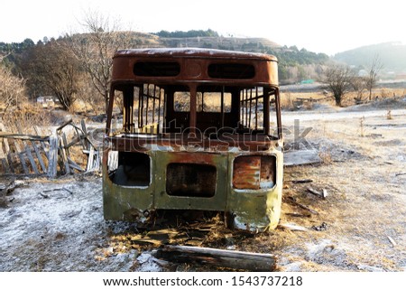 The skeleton of an abandoned old bus against the winter hills, old machinery