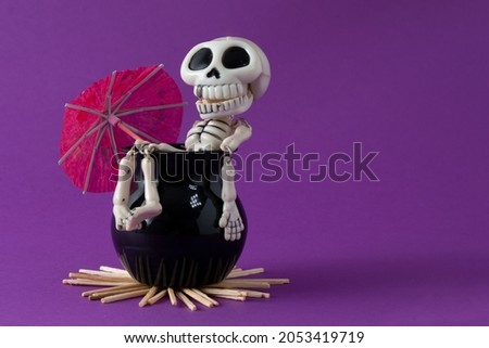 Skeleton in a cauldron that enjoys with an umbrella.