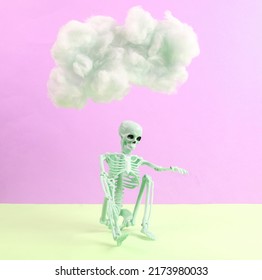 Skeleton With Cloud On Pastel Two Tone Background. Creative Idea. Minimal Concept. Pastel Color Trend