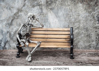Skeleton ghost sits sleepily on a an old bench with dark background gothic or loft style.
