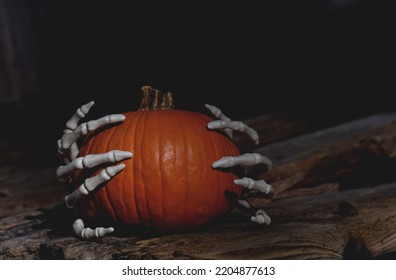 Skeleton Hands Grabbing Halloween Orange Pumpking In A Dark