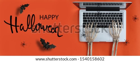 Skeleton hands typing in laptop and Happy Halloween text