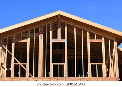 Skeleton of a house under construction showing the top floor and roofline against a blue sky.