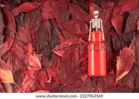 a skeleton of a man climbs out of a red vase, like a gin from a bottle. background red autumn leaves
