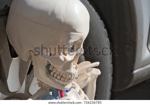 Skeleton is\
pensive. Car tire in the background.\

