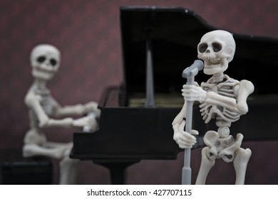 A skeleton singer with a skeleton pianist in the back