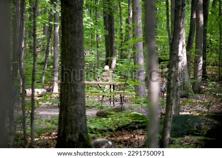 A skeleton spending some time in a campground sitting at a picnic table.