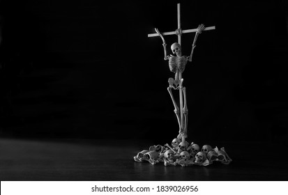 Skeleton Tied Up With Crucifix Wich Has Pile Of Skulls And Bone Below All Put On Dark Background Adjustment Color Black And White For Background 
 / Still Life Image, Select Focus, Space For Text

