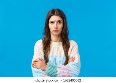 Skeptical, annoyed and displeased young woman hearing something stupid, nonsense, raise eyebrow suspicious and doubtful, cross hands over chest with disapproval, standing blue background