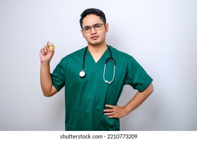 Skeptical And Displeased Asian Male Nurse Or Doctor Pointing And Showing Urine Pot Sample Isolated Over White Background