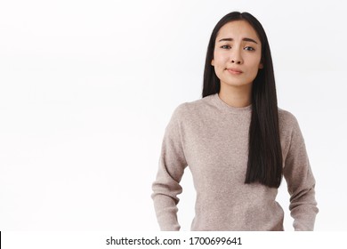 Skeptical good-looking asian female in 20s smirk dissatisfied and uncertain, having doubts, dont like idea, standing indecisive and questioned, feel bad about suspicious plan, white background