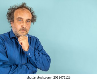 Skeptical Looking Man Mad Scientist Type With Blue Man Shirt And Wild Hair Against Light Blue Background