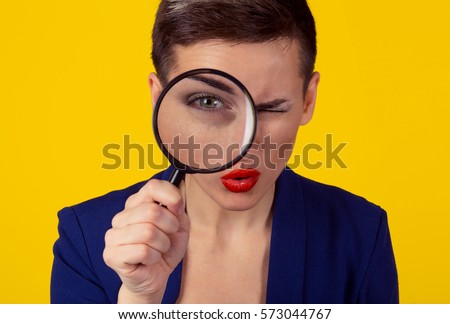 Skeptical woman looking through magnifying glass isolated yellow wall background. Funny woman skepticism concept. Positive human emotion face expression body language Focus on eye looking through lens