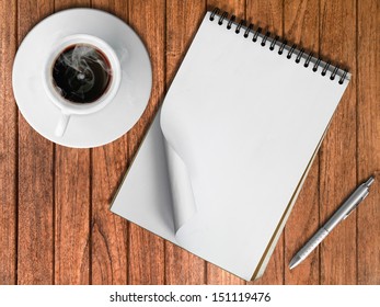 Sketch Book Silver Pen And White Cup Of Hot Coffee On Wood Table