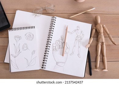 Sketchbook With Beautiful Drawings, Mannequin And Pencils On Wooden Table, Flat Lay