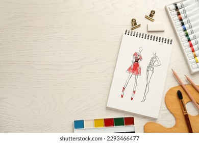 Sketches of different clothes in pad on white wooden table, space for text. Fashion designer's desk with stationery, flat lay - Powered by Shutterstock