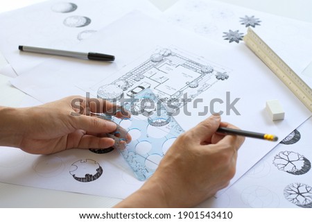 sketching by hands, layout plan and  plant symbols in landscape design or garden design or landscape architecture with black pen, circle template ruler, scale ruler and other tools, selective focus