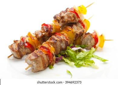 Skewered on wooden sticks tasty pork meat and vegetables mix, grilled meat on a white background 