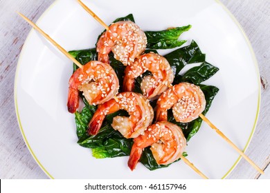 Skewered Sesame Shrimp On Spinach In White Plate. View From Above, Top Studio Shot