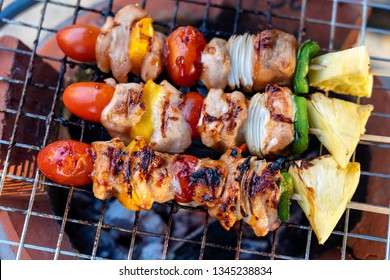 Skewers with pieces of grilled barbecue, green bell pepper, red tomato and meat for sell in street market, Thailand, close up