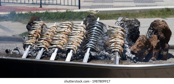 Skewers Of Sardines Over Incandescent And Smoky Embers In Malaga. Typical Food For Holidays And Beach In Spain.